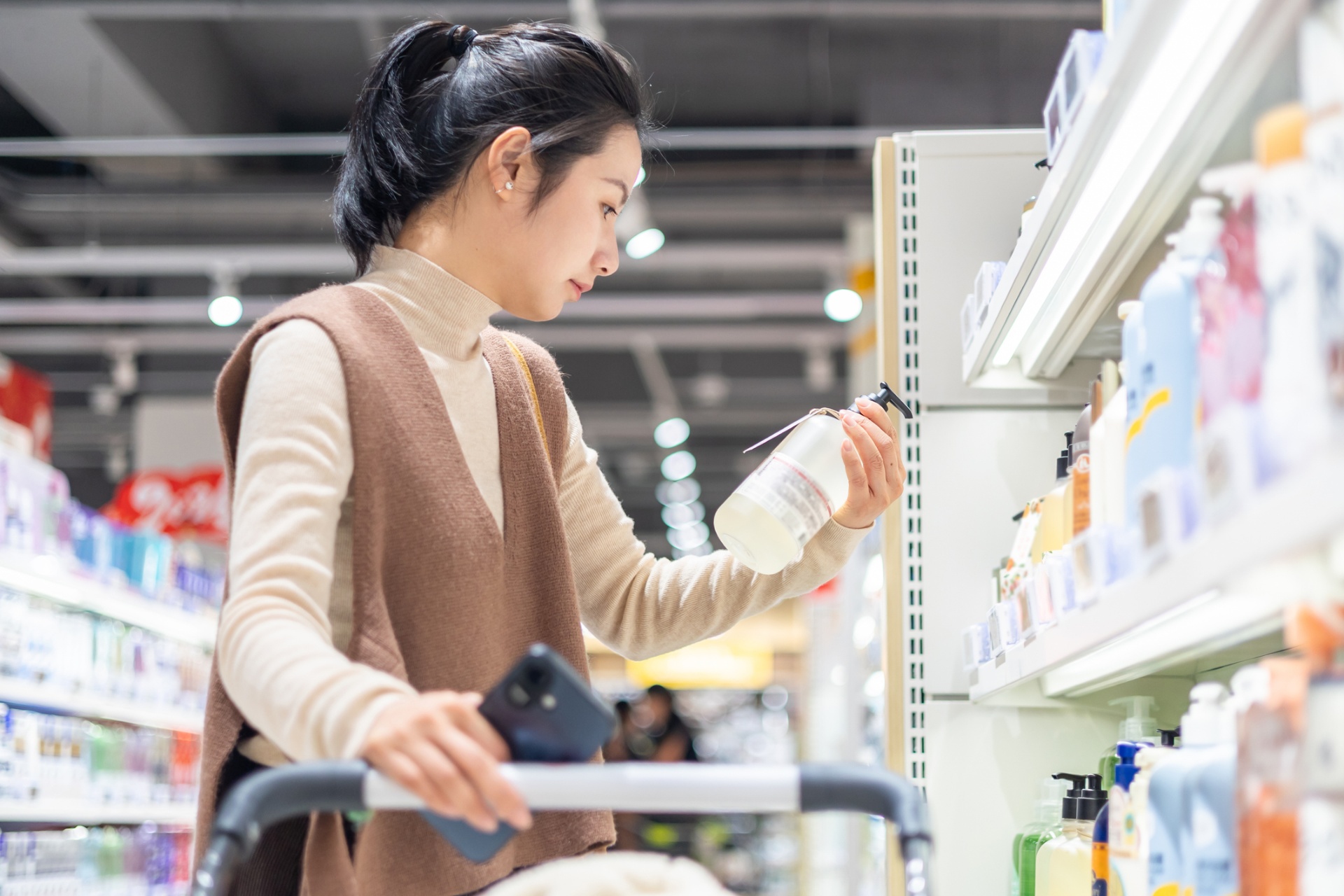 Shopper comparing consumer goods products on a supermarket shelf